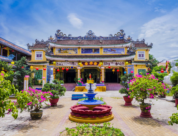 Amazing view of Chua Phap Bao Pagoda through a courtyard garden with flowers and bonsai trees, Hoi An, Vietnam - Photo, Image