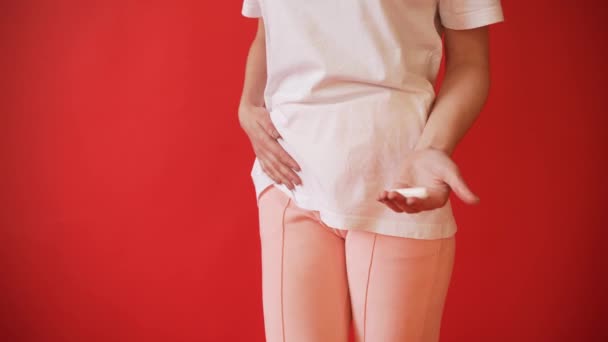 Поняття менструації, овуляції у дівчат. Дівчина на червоному тлі тримає тампон, прокладка
. - Кадри, відео
