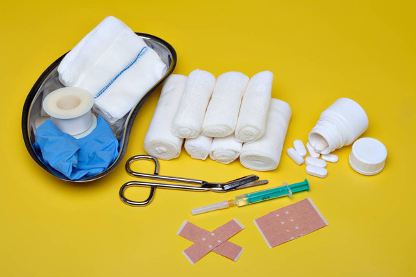 Plasters and bandages with Scissors and syringe on a yellow background - Fotoğraf, Görsel