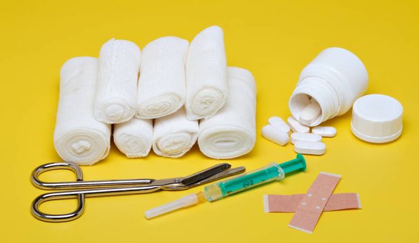 Plasters and bandages with Scissors and syringe on a yellow background - Photo, Image