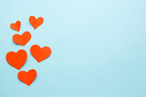 red paper hearts on a blue paper background - 写真・画像