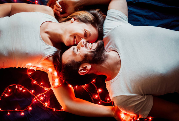 Νεαρό ζευγάρι ξαπλωμένο με Χριστουγεννιάτικα φώτα - Φωτογραφία, εικόνα