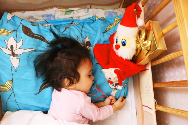 The child is sleeping at night. Nearby is a beautiful gift in the box. - Foto, Imagen