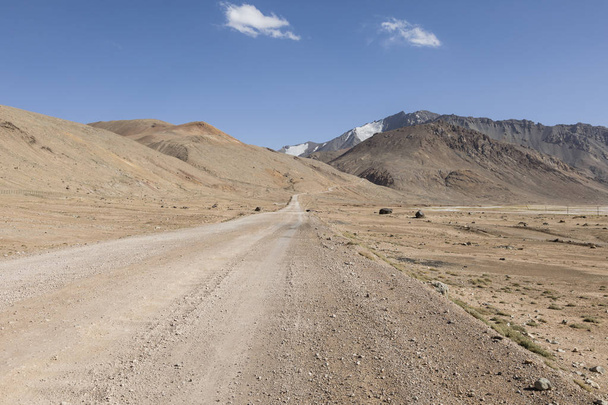 Пустынный пейзаж в районе перевала Ак-Байтал с дорогой в горах Памира в Таджикистане
 - Фото, изображение