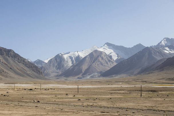 Pouštní krajina v oblasti Ak-Baital Pass se silnicí v pohoří Pamír v Tádžikistánu - Fotografie, Obrázek