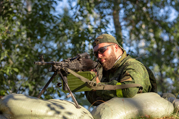 francotirador armado con un gran calibre, rifle de francotirador, disparando objetivos enemigos en el rango de refugio, sentado en una emboscada
 - Foto, imagen