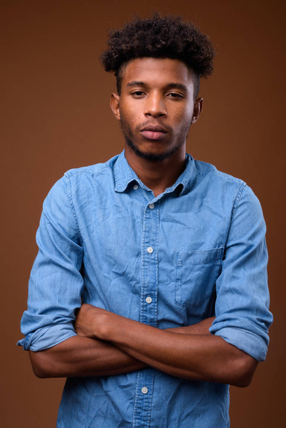 Młody przystojny mężczyzna Afryki na brązowym tle - Zdjęcie, obraz