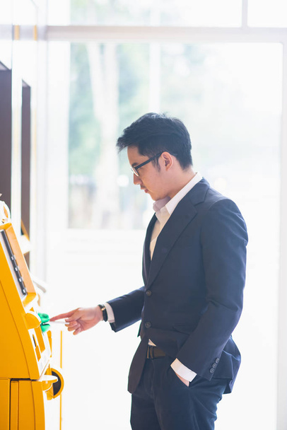 Бизнесмен снимает наличные у банкомата
 - Фото, изображение