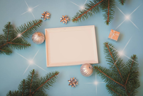 白フレーム、シルバー色のクリスマスの装飾と青い背景上のモミの枝。フラット横たわっていた、トップ ビュー. - 写真・画像
