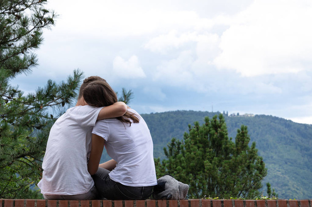 Dağlar yüksek katlı bir binanın kenarına bir arka plan üzerinde bir kız adam hugs. - Fotoğraf, Görsel