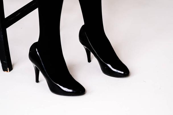 women's feet in black stockings or tights, black high-heeled shoes  - Fotó, kép