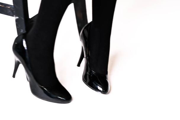 women's feet in black stockings or tights, black high-heeled shoes  - Фото, изображение
