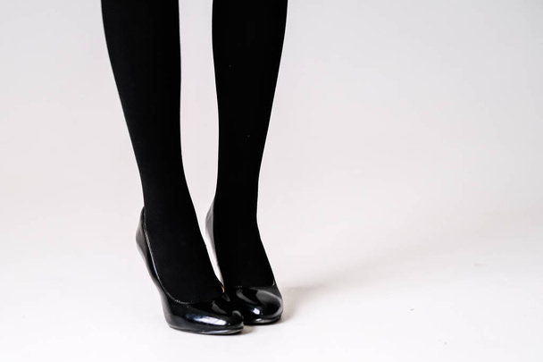 women's feet in black stockings or tights, black high-heeled shoes  - Zdjęcie, obraz