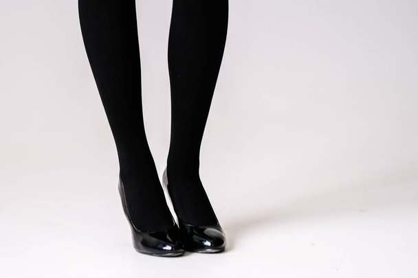 women's feet in black stockings or tights, black high-heeled shoes  - Zdjęcie, obraz