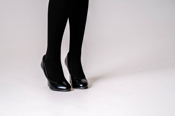 women's feet in black stockings or tights, black high-heeled shoes  - Fotó, kép