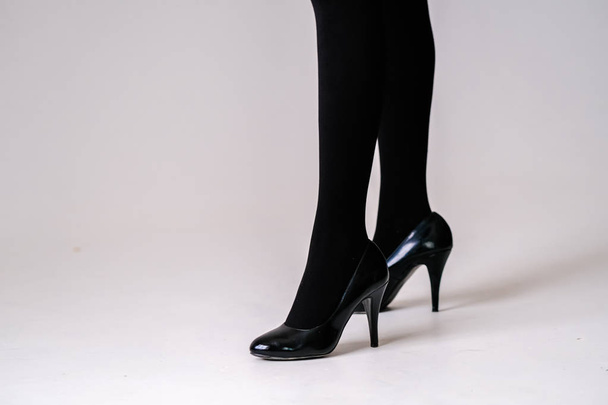 women's feet in black stockings or tights, black high-heeled shoes  - Foto, afbeelding