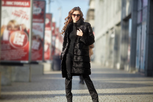 The girl walks through the city in a fur coat - 写真・画像