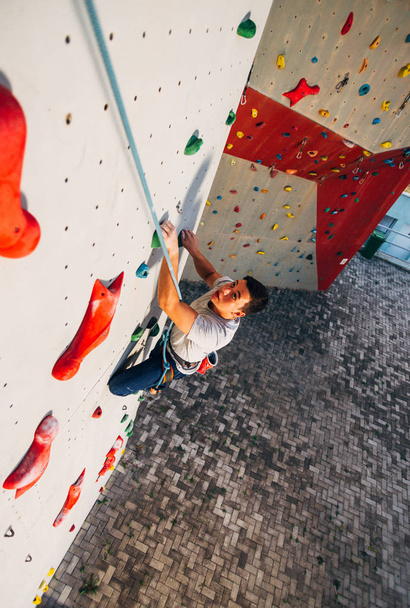 Hombre con soga, trepando sobre un muro de escalada muy alto
 - Foto, Imagen