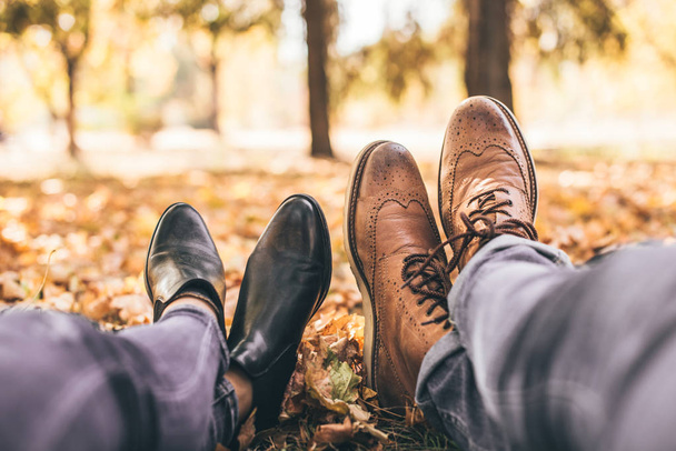 Ένα νεαρό ζευγάρι ξεκουράζεται στο πάρκο δείχνει τις μπότες τους - Φωτογραφία, εικόνα