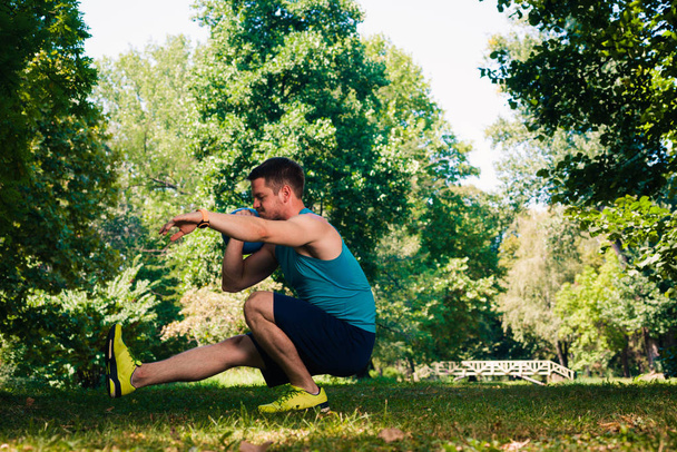 Atractivo instructor de fitness haciendo ejercicio de peso pesado con kettlebell en el parque
 - Foto, Imagen