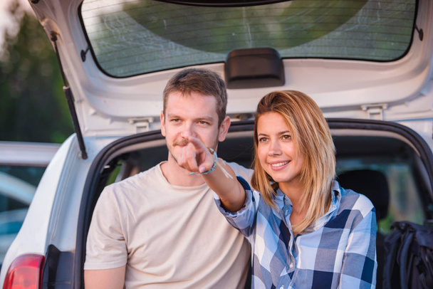 Jovem casal sentado na parte de trás de um veículo off-road e desfrutando da vista de dentro do veículo todo o terreno ao pôr do sol
. - Foto, Imagem