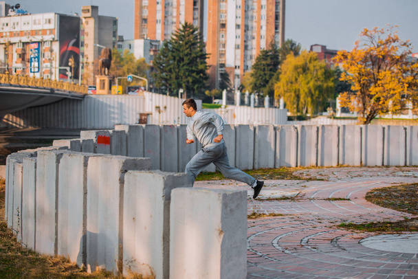 Entraînement d'un parkour sautant par-dessus un haut mur de béton en milieu urbain
 - Photo, image