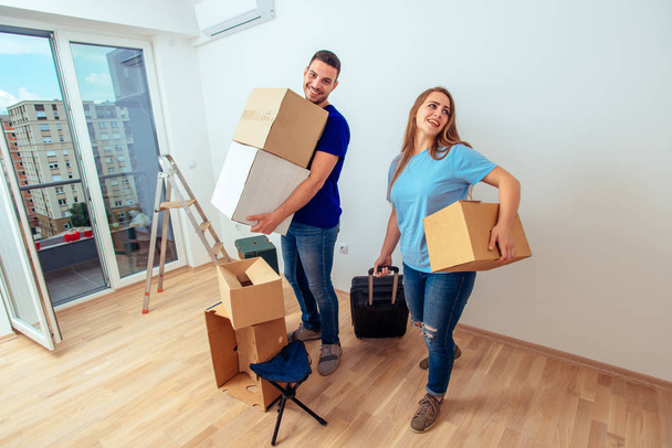 Jeune couple excité avec bagages et boîtes déménagent dans une nouvelle maison
 - Photo, image
