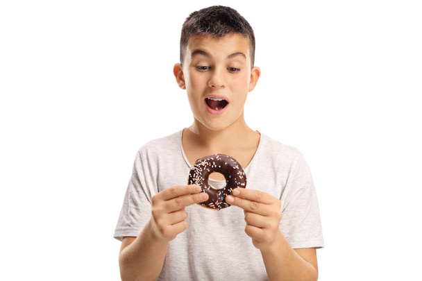 Teenage boy holding a chocolate donut about to bite it isolated on white background - Foto, Imagen