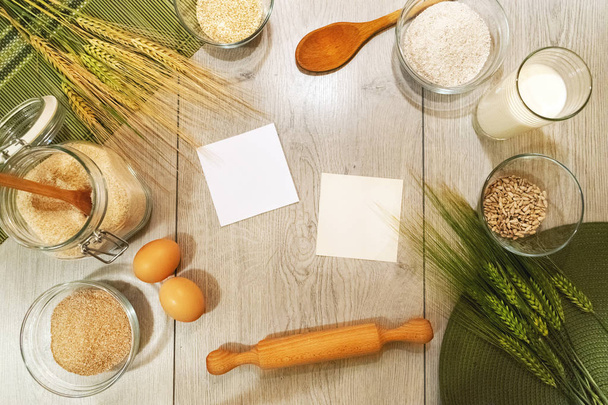 Verse ingrediënten van gerst-, tarwe-, bakkerij- en brood op houten achtergrond met lege notes, bovenaanzicht - Foto, afbeelding