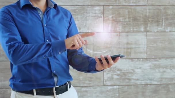 Man aktiviert ein konzeptuelles Hud-Hologramm mit Textspiel. der Typ im blauen Hemd und der hellen Hose mit einem holographischen Bildschirm auf dem Hintergrund der Wand - Filmmaterial, Video