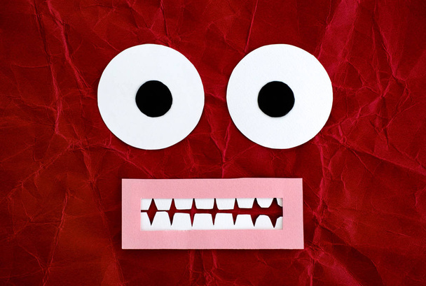 Scared emotional face made from paper. Red background. - Foto, afbeelding