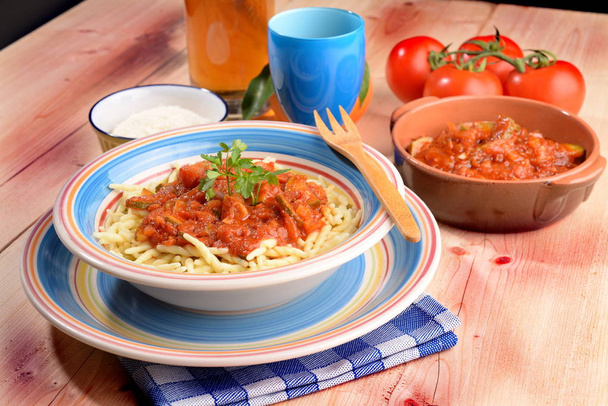 Plat de pâtes trofie aux tomates avec courgettes sur la table
 - Photo, image