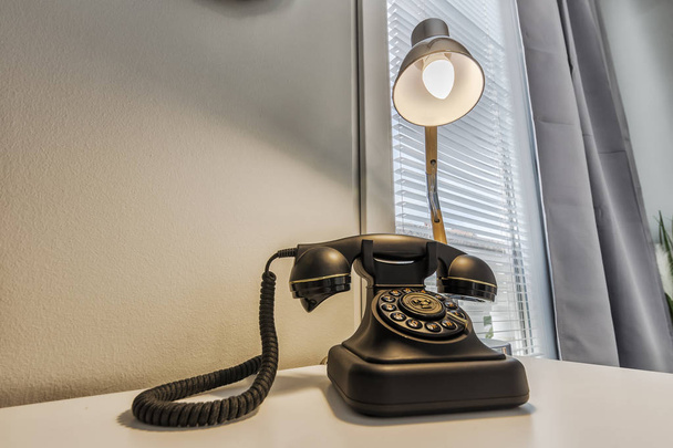 telefone retro velho e lâmpada de mesa na mesa de madeira
 - Foto, Imagem