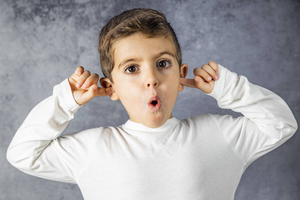 Porträt eines kleinen Jungen, der seine Ohren bedeckt - Foto, Bild