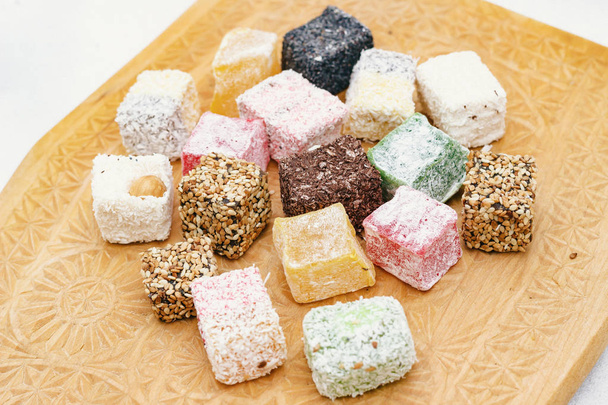Assorted Turkish delight on a carved wooden board, close-up - Valokuva, kuva