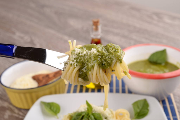 Plaat van spaghetti met pesto en basilicum laat op de tafel - Foto, afbeelding