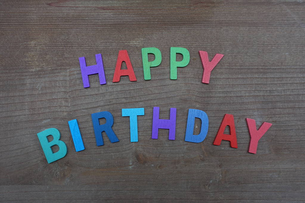 Feliz cumpleaños con letras de madera multicolores sobre un tablero de madera
 - Foto, Imagen