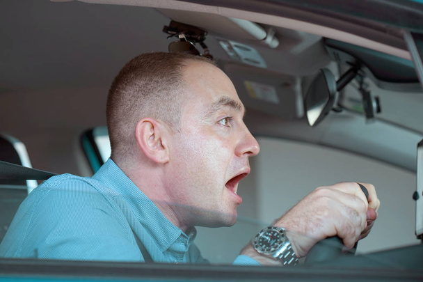 Boční okna pohled nezkušené nervózní motorista. Mladý muž řídit auto šokován mít dopravní nehodu, čelní pohled. Strach, vtipné hledají mladého muže řidič v autě. - Fotografie, Obrázek