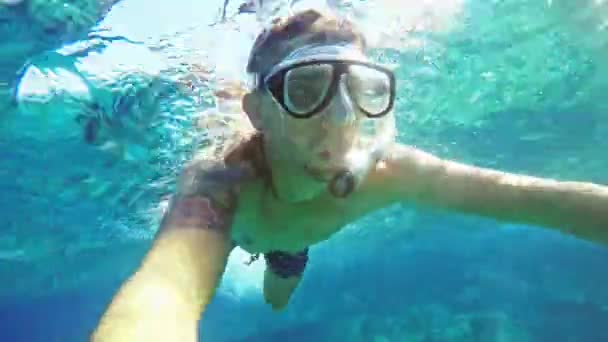 Podwodne selfie, człowiek nurkowania w maska do nurkowania z rurką i nurkować z rurką w wodzie jasne błękitne morze. Patrzy w kamerę - Materiał filmowy, wideo