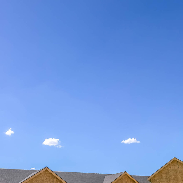 Дах будинку на тлі яскравого блакитного неба з хмарами
 - Фото, зображення