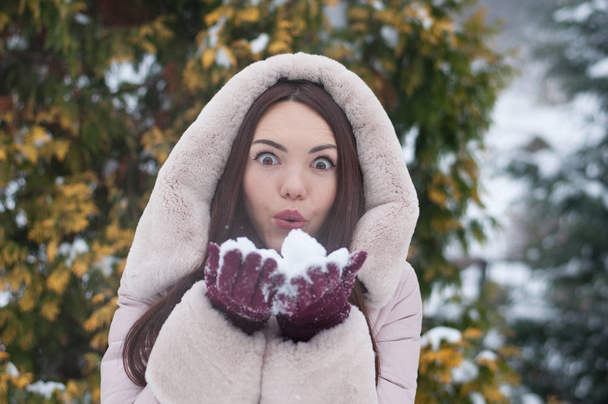 Portret młodej pięknej kobiety emocjonalne w dół płaszcz i rękawice na śniegu objętych ogród tła. Pejzaż zimowy śnieżny - Zdjęcie, obraz