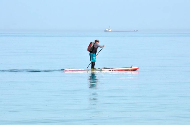 duel of a man and a steamer - oh I'll catch up ...  surfing, board, rowing standing - Photo, Image