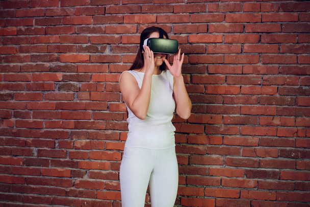 Virtual reality device. Woman playing game in virtual reality glasses. Headset with virtual screen. Girl touch something using modern glasses with virtual screen. - Photo, Image