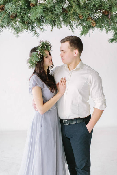 portrait of lovely couple on white wall background and pine decoration - Foto, immagini