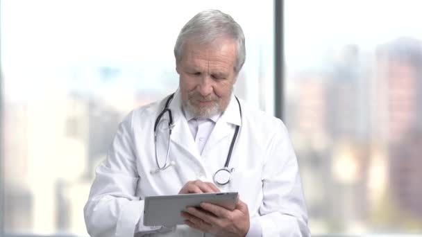 Alegre médico senior usando tableta digital
. - Imágenes, Vídeo