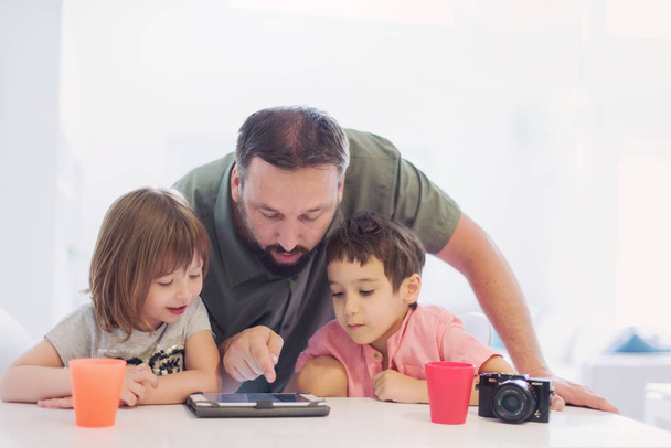 single father at home with two kids playing games and giving education lessons on tablet  computer at modern home - Foto, immagini