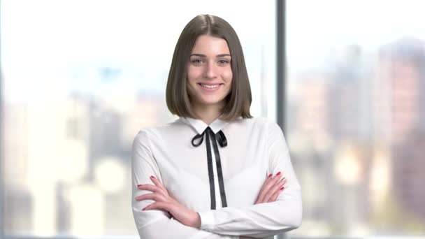 Attractive young lady with crossed arms. Happy smiling young business woman wearing white chiffon blouse on blurred background. Smiling young corporate. - Footage, Video