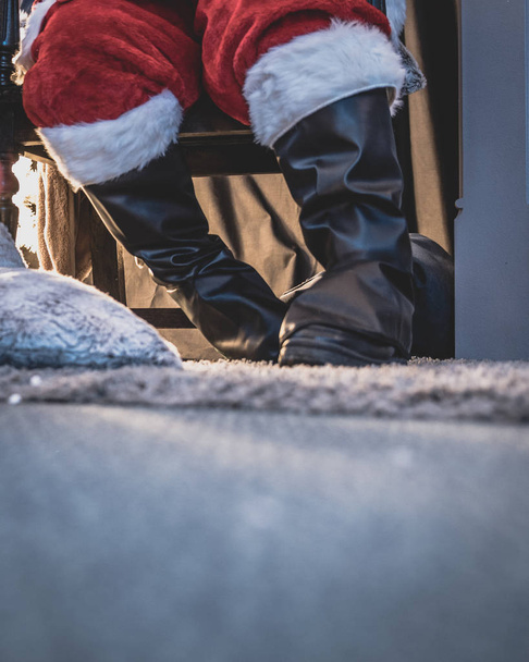 Χαμηλή γωνία προβολής των ποδιών του Αϊ-Βασίλη που δίνει μακριά δώρα στα παιδιά στο σπήλαιο του Αϊ-Βασίλη, κατά τη διάρκεια της περιόδου που προηγείται των Χριστουγέννων. - Φωτογραφία, εικόνα