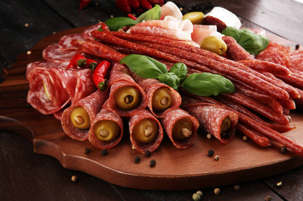 Food tray with delicious salami, pieces of sliced prosciutto crudo, sausage and basil. Meat platter with selection. - Fotografie, Obrázek
