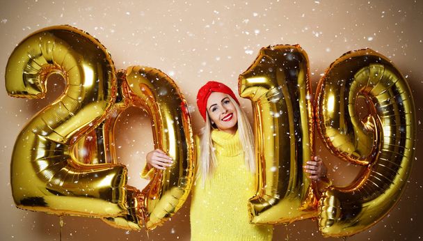 Woman celebrating New Year xmas party happy laughing in yellow sweater blouse with 2019 gold balloons  - Zdjęcie, obraz